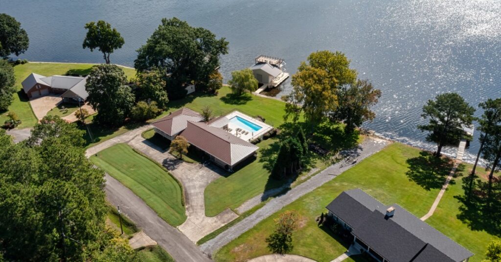 An aerial view shows neighboring waterfront homes beside a lake, with docks and clear shoreline access.