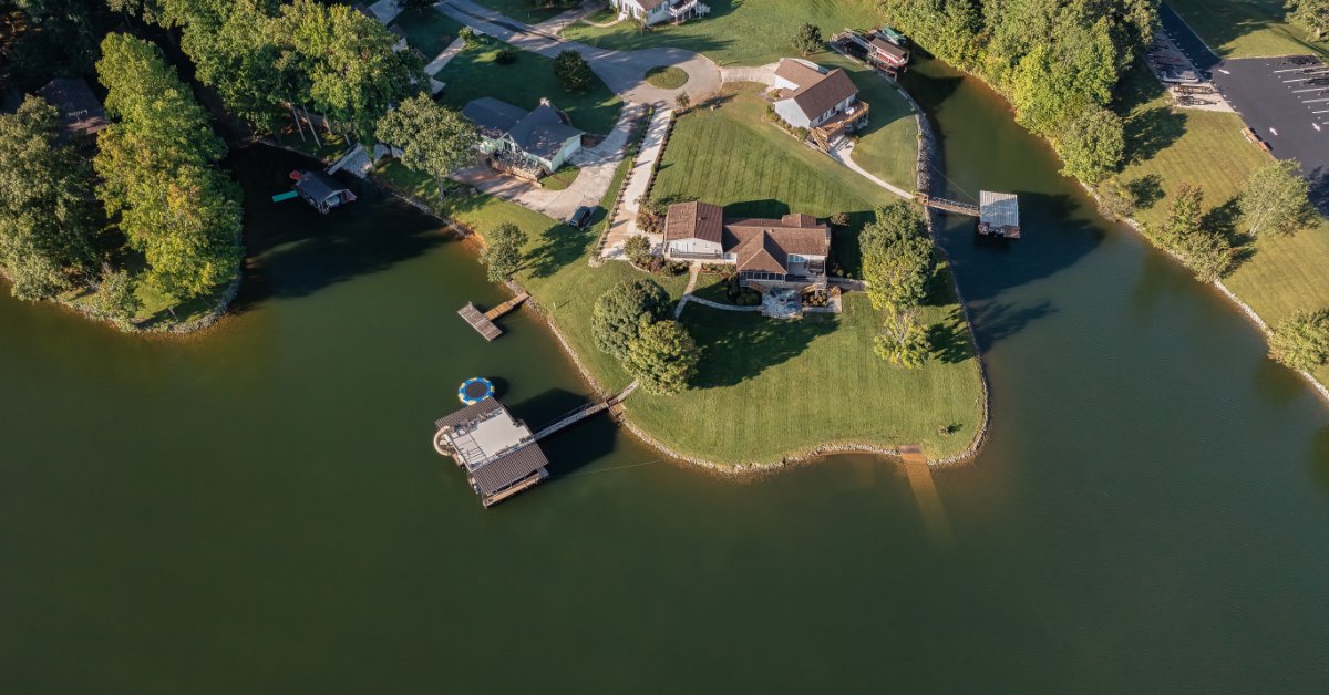 An aerial view shows several waterfront homes with individual docks extending from their properties into the lake.