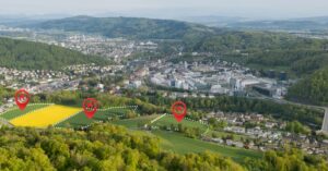 An aerial view shows several marked parcels of open land near residential neighborhoods and a developed urban area.