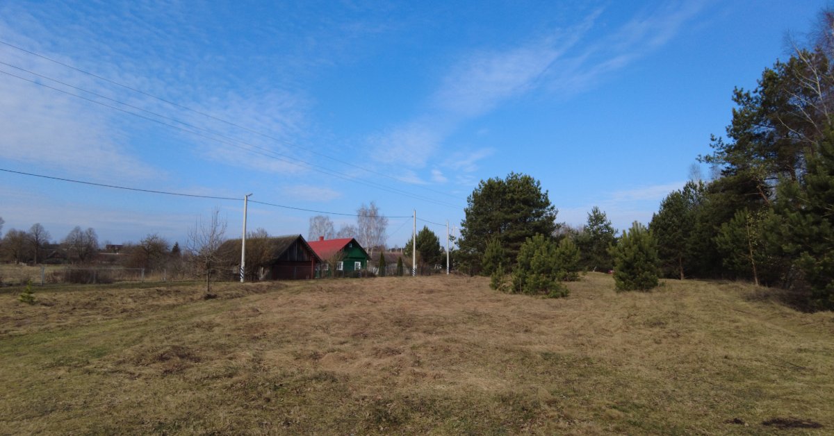 Electrical lines cross an open rural property with scattered trees and several homes visible in the distance.